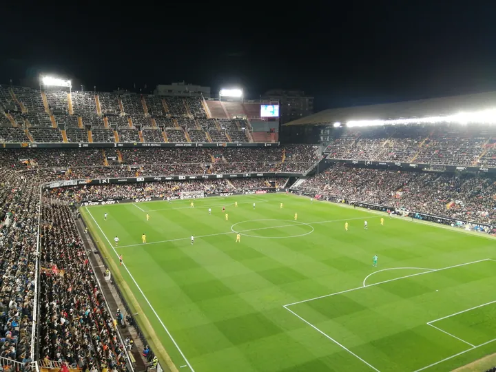 Estádio de Mestalla iluminado e cheio durante um jogo noturno do Valência contra o Barcelona