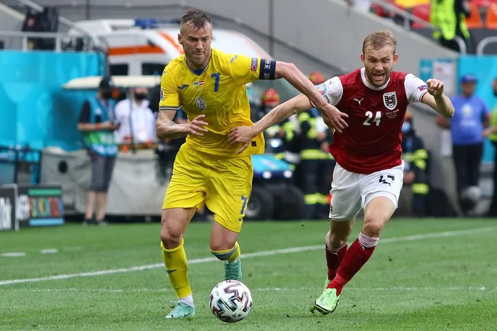 Capitão da Ucrânia com a bola perante um jogador da Áustria no Euro 2020